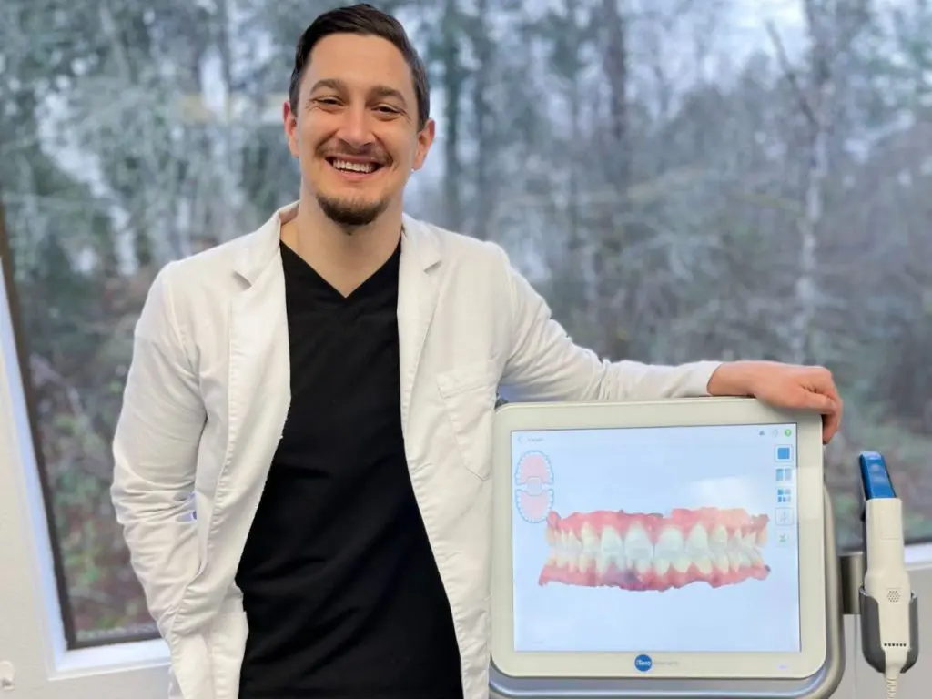 A portrait of Dr. Cameron Freelove, standing beside his dental rendering device explaining about Everything You Need to Know About Your Retainer