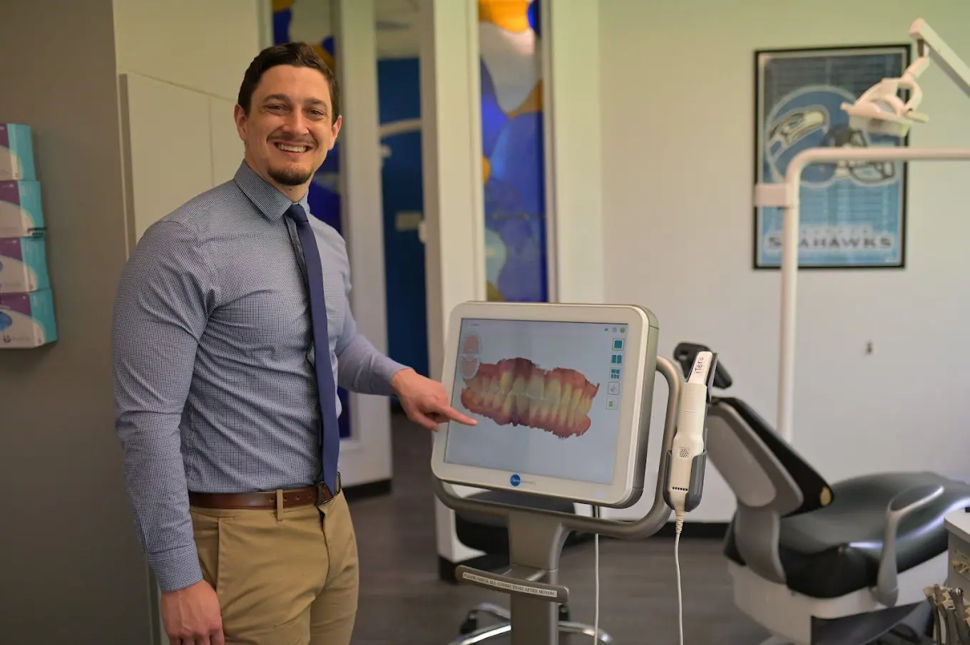 A portrait of Dr. Cameron Freelove, DDS standing in front of dental rendering device in his office in Sammamish or Kent, WA.