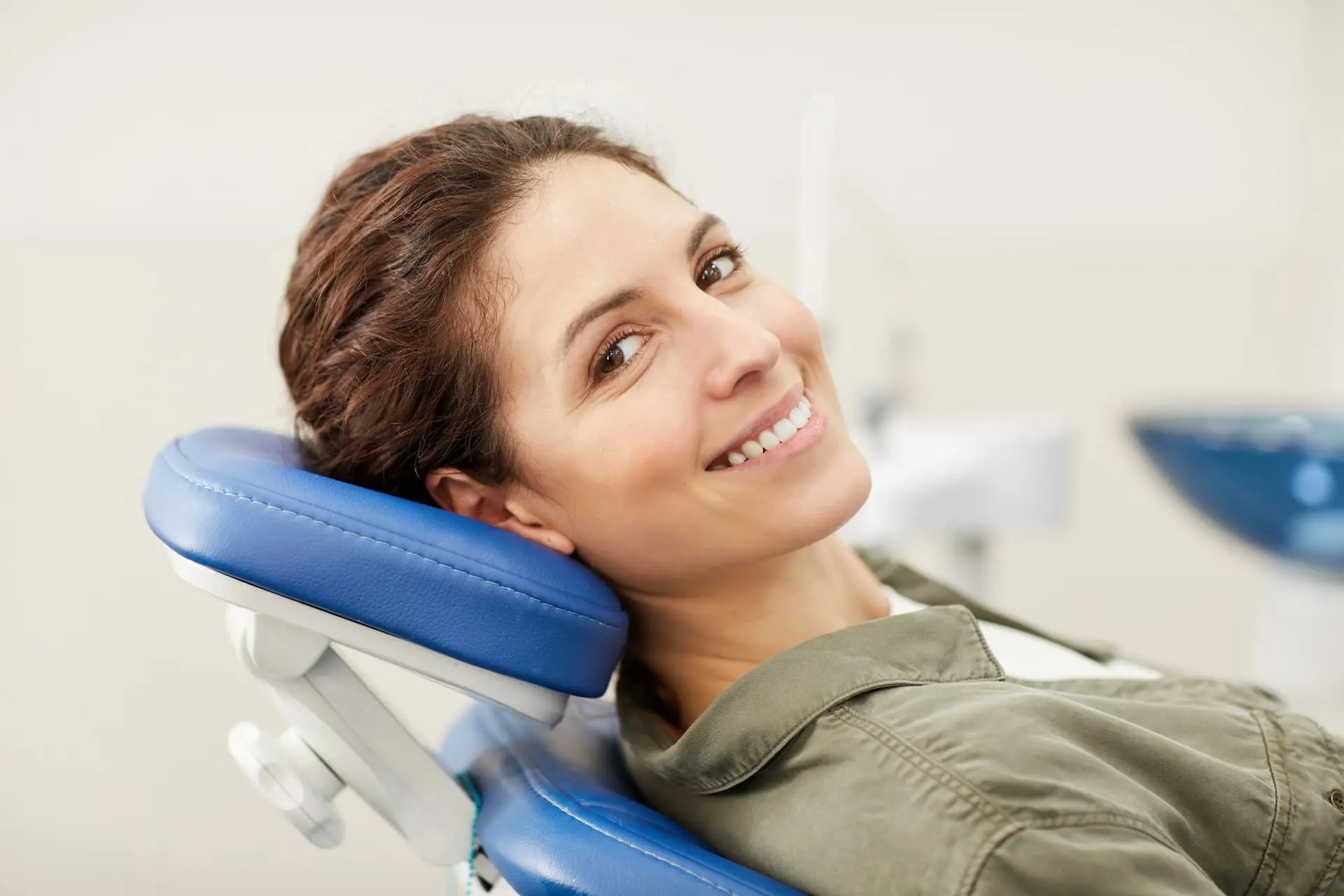 Woman smiling while sitting in a reclining dental chair.
