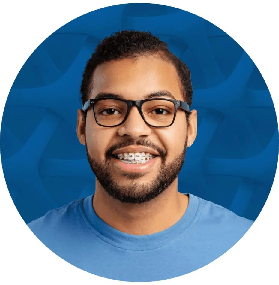 Man with glasses and braces smiling, wearing a blue shirt against a blue background. Illustrating Braces Cost Sammamish or Kent, WA