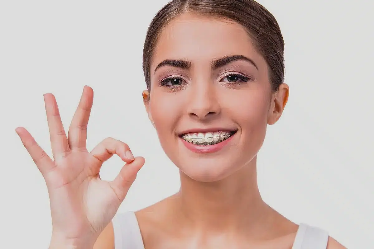 A woman with braces smiles while making an "okay" gesture with her hand in Sammamish or Kent, WA.