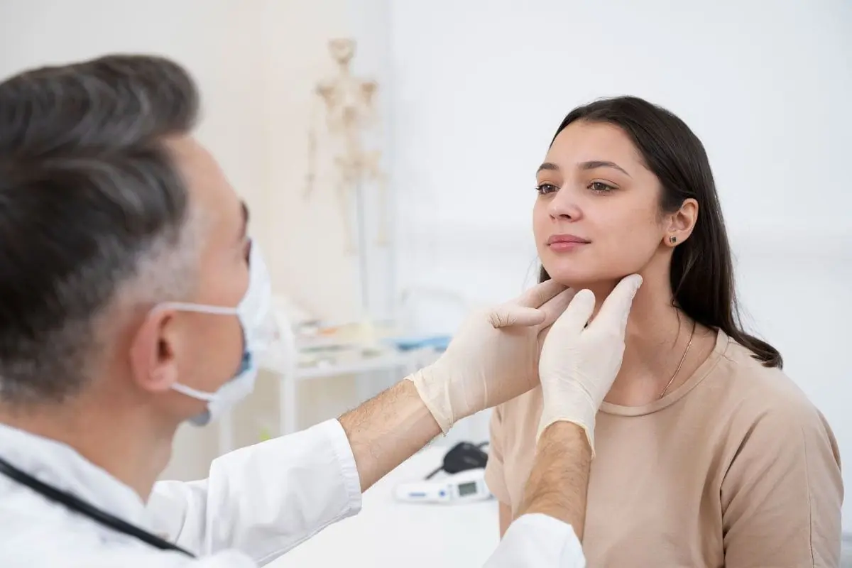 A doctor examines a woman's neck after jaw surgery orthodontics in Kent or Sammamish, WA, looking for abnormalities, while wearing surgical gloves and a mask in a clinical setting.