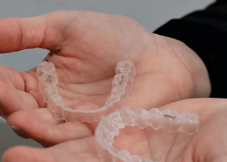 Person holding two clear dental aligners in their hands. Illustrating Invisalign Payment Plan in Sammamish or Kent, WA