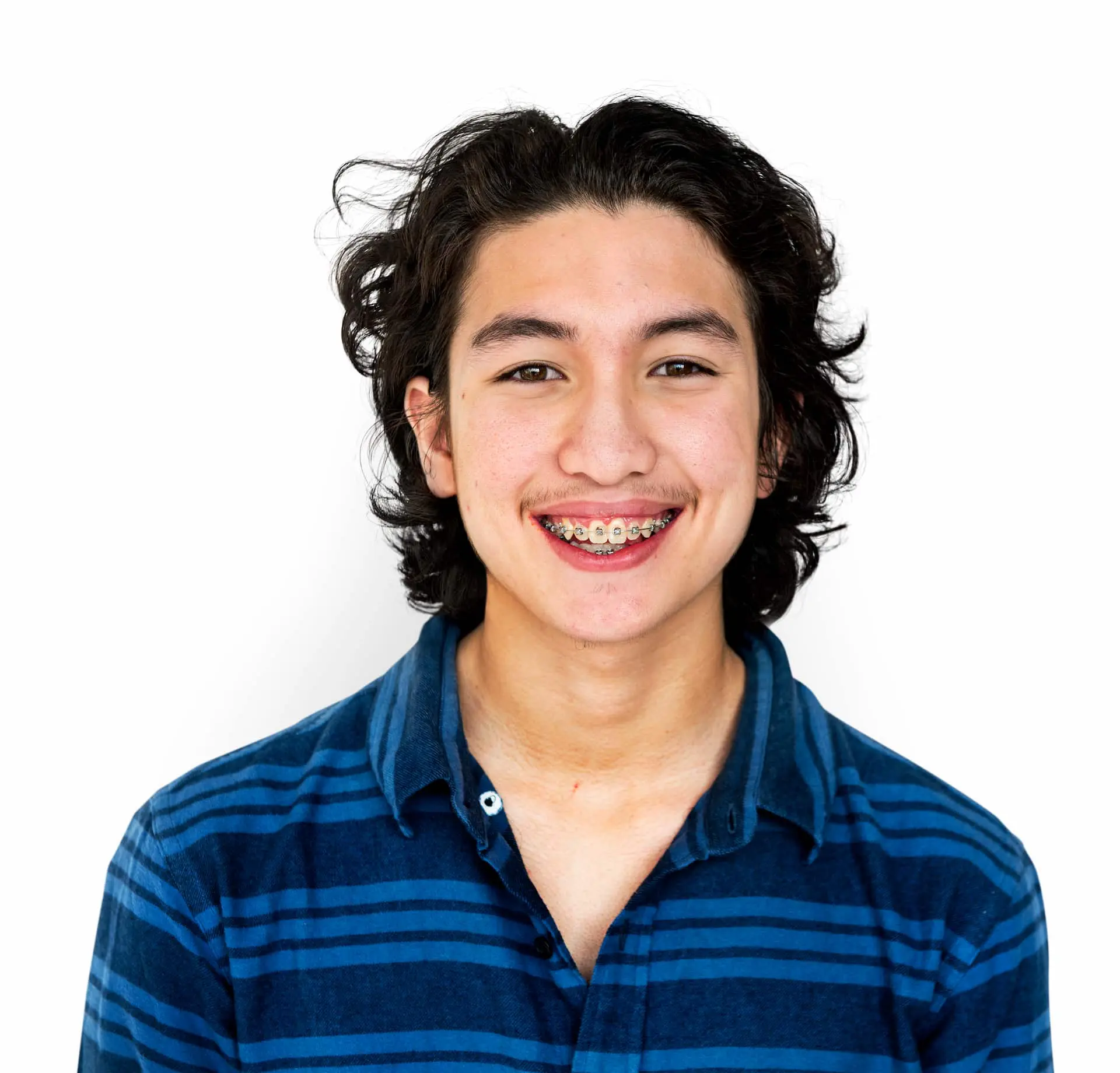Person with braces smiling, wearing a blue striped shirt against a plain white background. Illustrating adult braces in Sammamish and Kent, WA