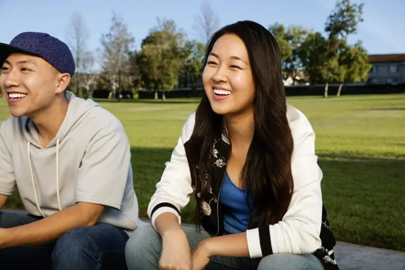 Two people sitting on the grass, smiling and enjoying a sunny day in a park near orthodontist in Sammamish or Kent, WA.