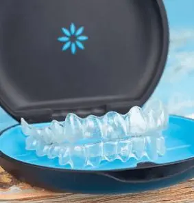 Invisalign clear aligners shown inside an open black and blue case with a floral logo illustrating Invisalign Payment Plan in Sammamish or Kent, WA