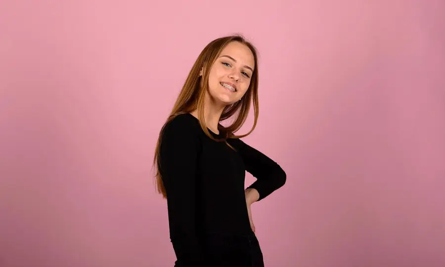 A person with long hair in a black outfit stands with one hand on their hip, smiling in Sammamish or Kent, WA.