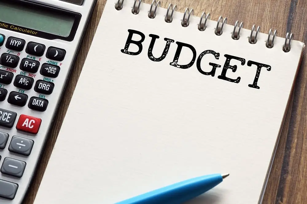 A calculator lies next to a notebook, opened to a page with the word "BUDGET" written at the top for braces payment plan at Freelove orthodontics in Sammamish or Kent, WA.