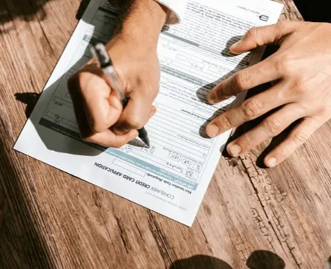 Person filling out an Invisalign insurance application form on a wooden table in Sammamish or Kent, WA.