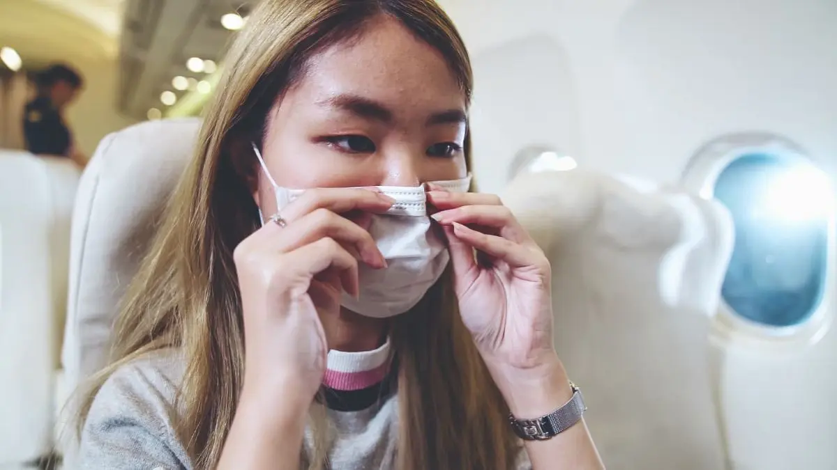 A person adjusts their mouth breather face mask while sitting in an airplane seat near orthodontist in Sammamish and Kent, WA.